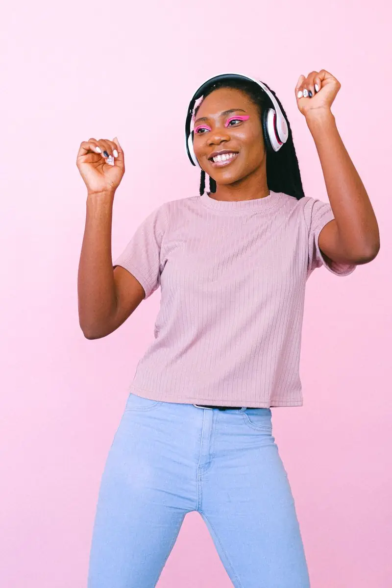 Jeune femme qui danse avec un casque sur fond rose