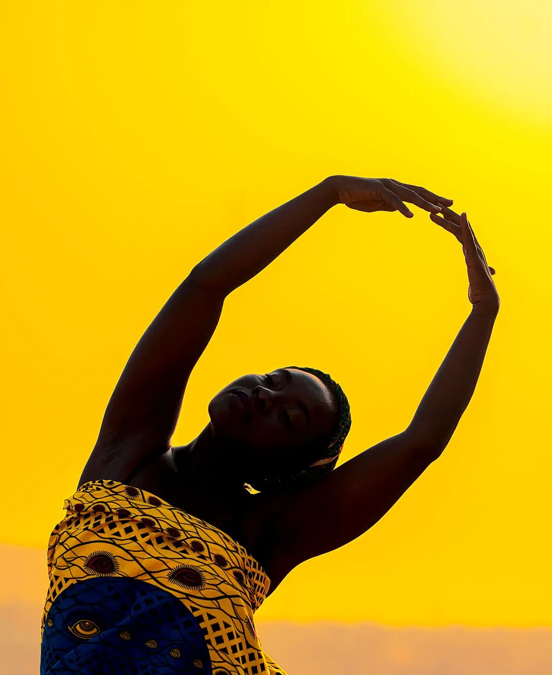Danseuse en mouvement, bras en arc, devant un ciel jaune